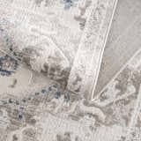Close-up of the Bakir Area Rug. Machine woven rug in blue and gray with a traditional pattern and textured pile. Fold