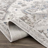 Close-up of the Bakir Area Rug, a machine-woven rug in blue and gray with a traditional design and visible rug backing. Fold
