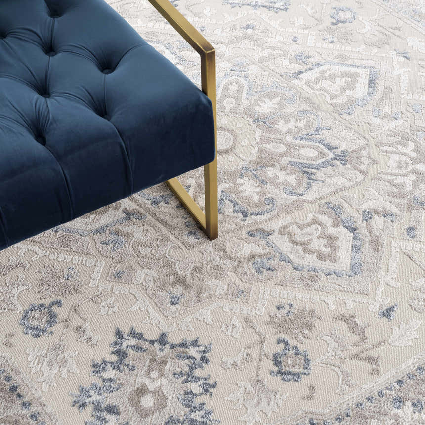 Close-up of the Bakir Area Rug showing its traditional blue and gray pattern and soft texture next to a blue chair. Styleshot