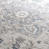 Close-up of the Bakir Area Rug. Traditional blue and gray floral pattern on a textured, machine-woven rug. Texture