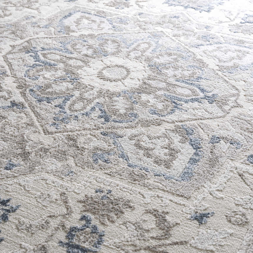 Close-up of the Bakir Area Rug. Traditional blue and gray floral pattern on a textured, machine-woven rug. Texture