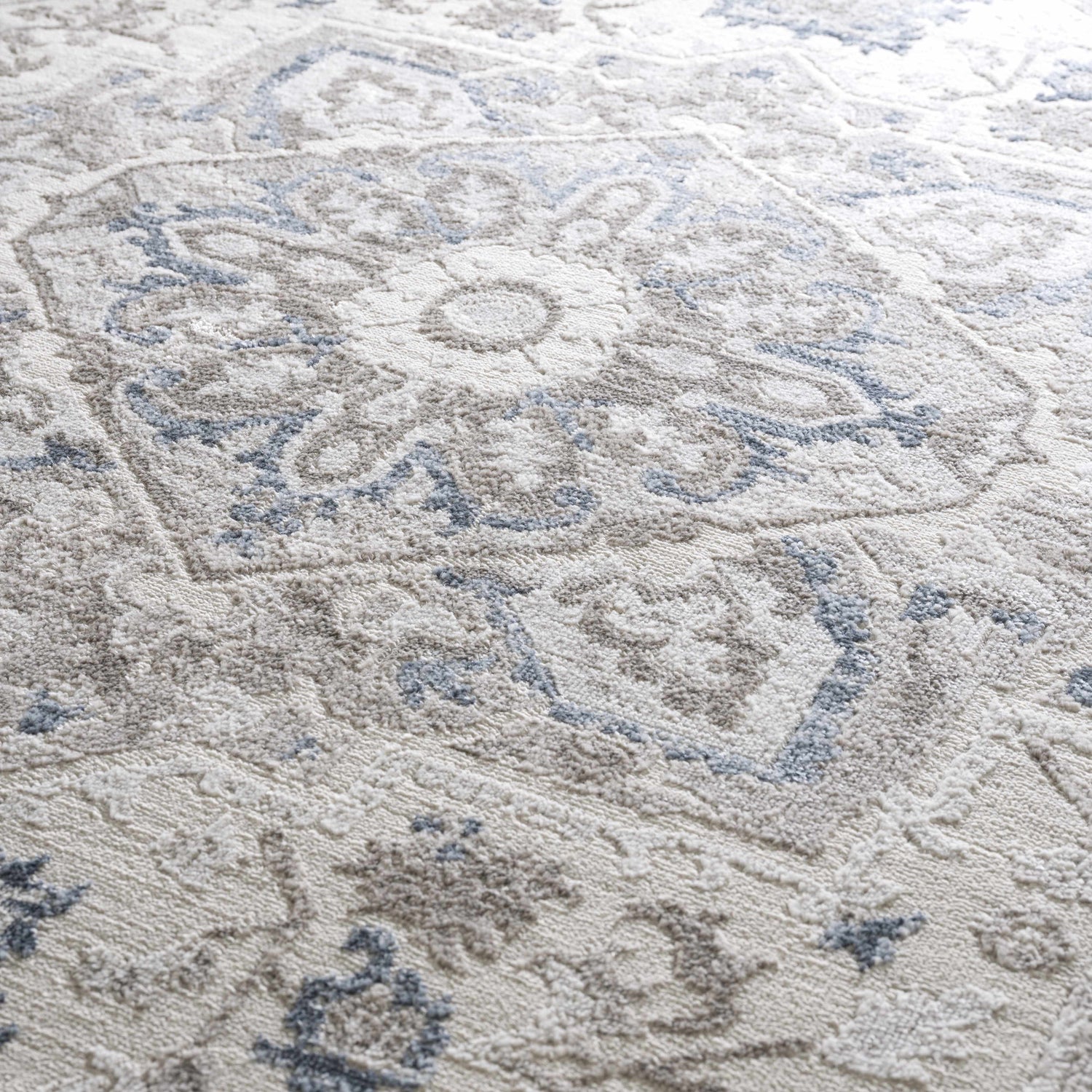 Close-up of the Bakir Area Rug. Traditional blue and gray floral pattern on a textured, machine-woven rug. Texture