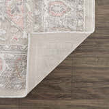 Close-up of a Damla Area Rug showing gray and pink vintage pattern, texture, and backing on wood floor. Fold
