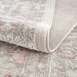 Close-up of the Damla Area Rug showing its gray and pink vintage pattern and soft, textured pile. Fold