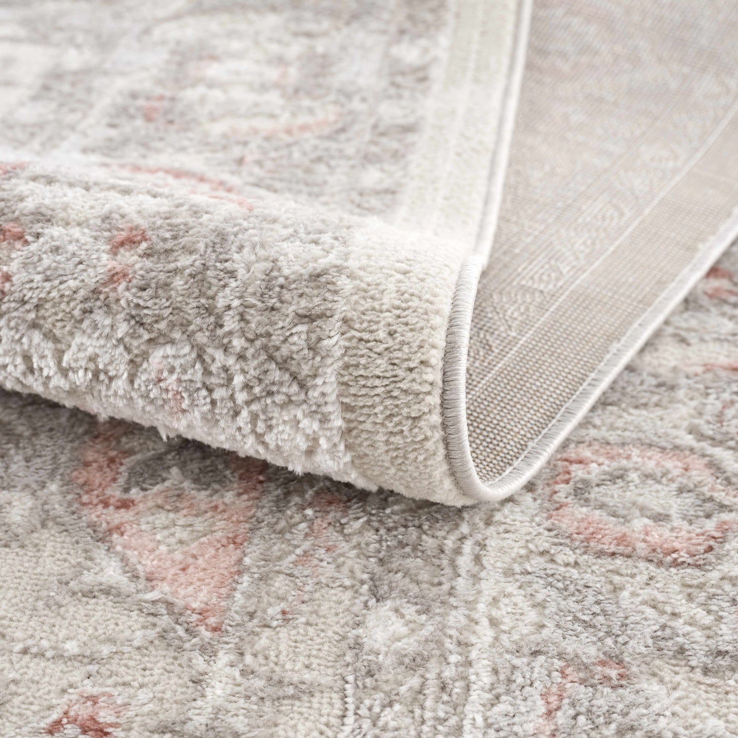 Close-up of the Damla Area Rug showing its gray and pink vintage pattern and soft, textured pile. Fold