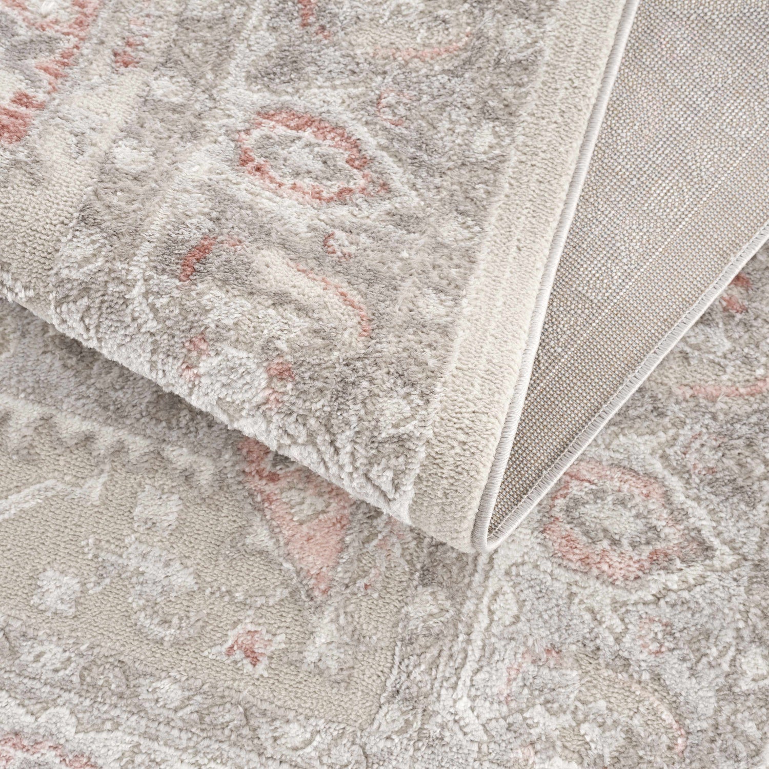 Close up of the Damla Area Rug in gray and pink, showing the traditional pattern and soft texture. Fold