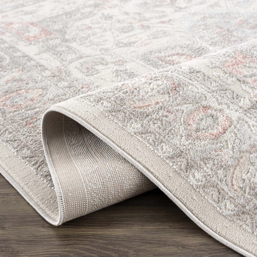 Close-up of the Damla Area Rug showing its gray and pink traditional pattern and machine woven construction. Fold