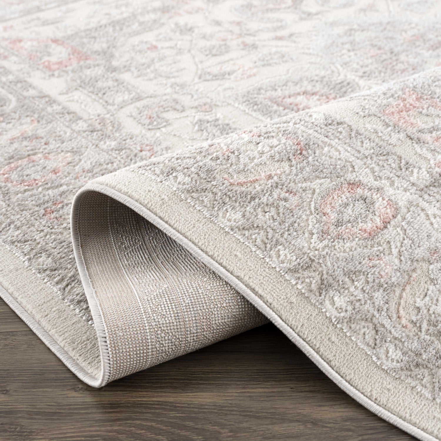 Close-up of the Damla Area Rug showing its gray and pink traditional pattern and machine woven construction. Fold