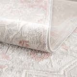 Close-up of the thick, textured Calum Pink Floral Area Rug. Features a gray and pink traditional floral pattern. Fold