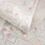 Close-up of the Calum Pink Floral Area Rug showing its thick, textured weave and gray and pink traditional pattern. Fold