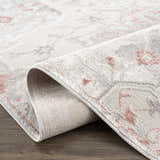 Close-up of the Calum Pink Floral Area Rug showing the gray, pink, and floral traditional design and machine-woven texture. Fold