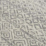 Close-up of the Gravelbourg Washable Boho Rug. Gray and light gray geometric pattern. Soft, textured polyester material. Texture