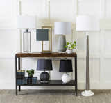 Entryway scene with a charcoal Angie Area Rug, console table with lamps, books, and plants against a white paneled wall. Styleshot