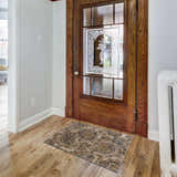 Entryway with a Morinville Teal Floral Rug in front of a vintage wood door and hardwood floors. Roomscene-Rectangle