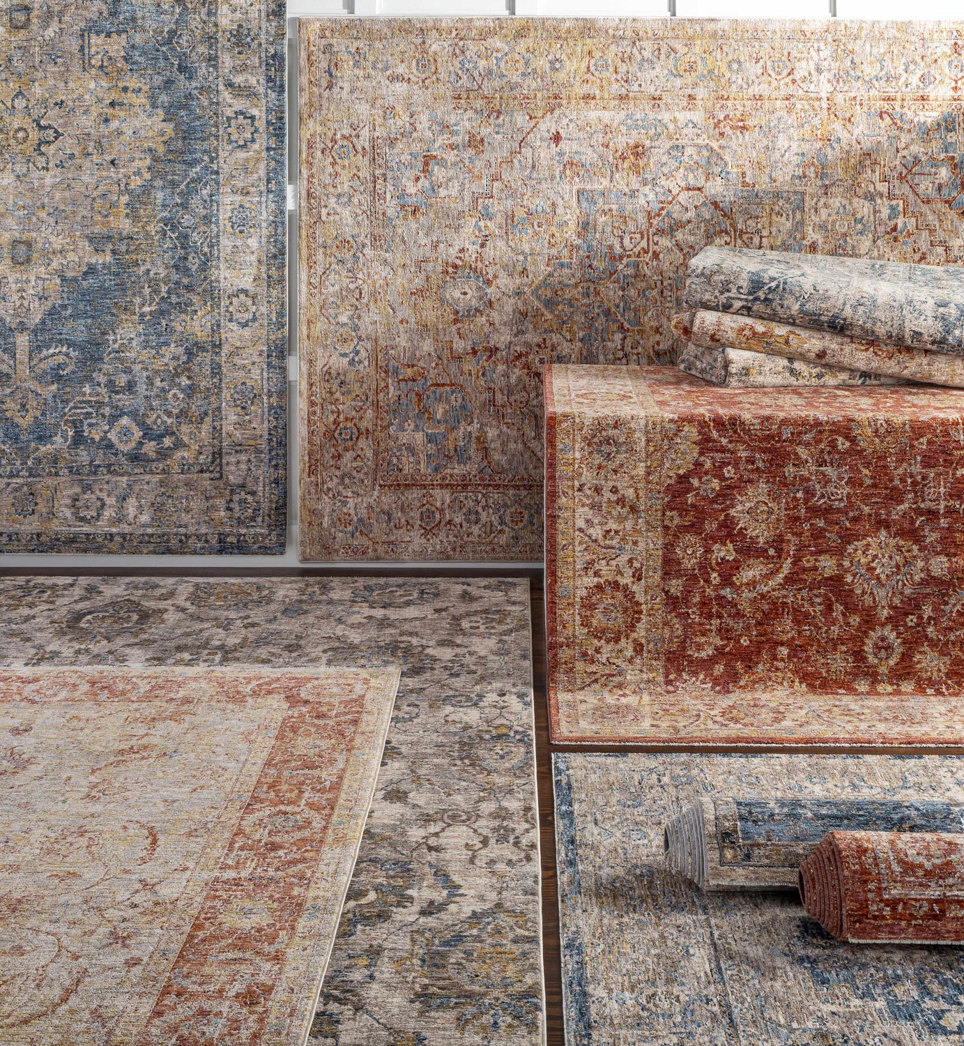 Assorted Kilsby Area Rugs. Traditional patterns in blue, rust, and beige. Rolled and flat rug textures. Styleshot