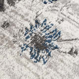 Close-up of the Duena Area Rug showing its light gray and blue traditional floral pattern and soft polypropylene texture. Texture