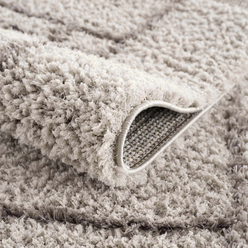 Close-up of the plush, silver gray Andia Gray Area Rug showing its shag texture and machine-woven backing. Fold