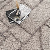 Close-up of the silver gray Andia Area Rug, a geometric shag rug with books and a vase on top. Styleshot