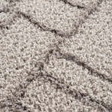 Close-up of the plush Andia Gray Area Rug, showing its geometric shag design and soft, silver and gray polyester texture. Texture