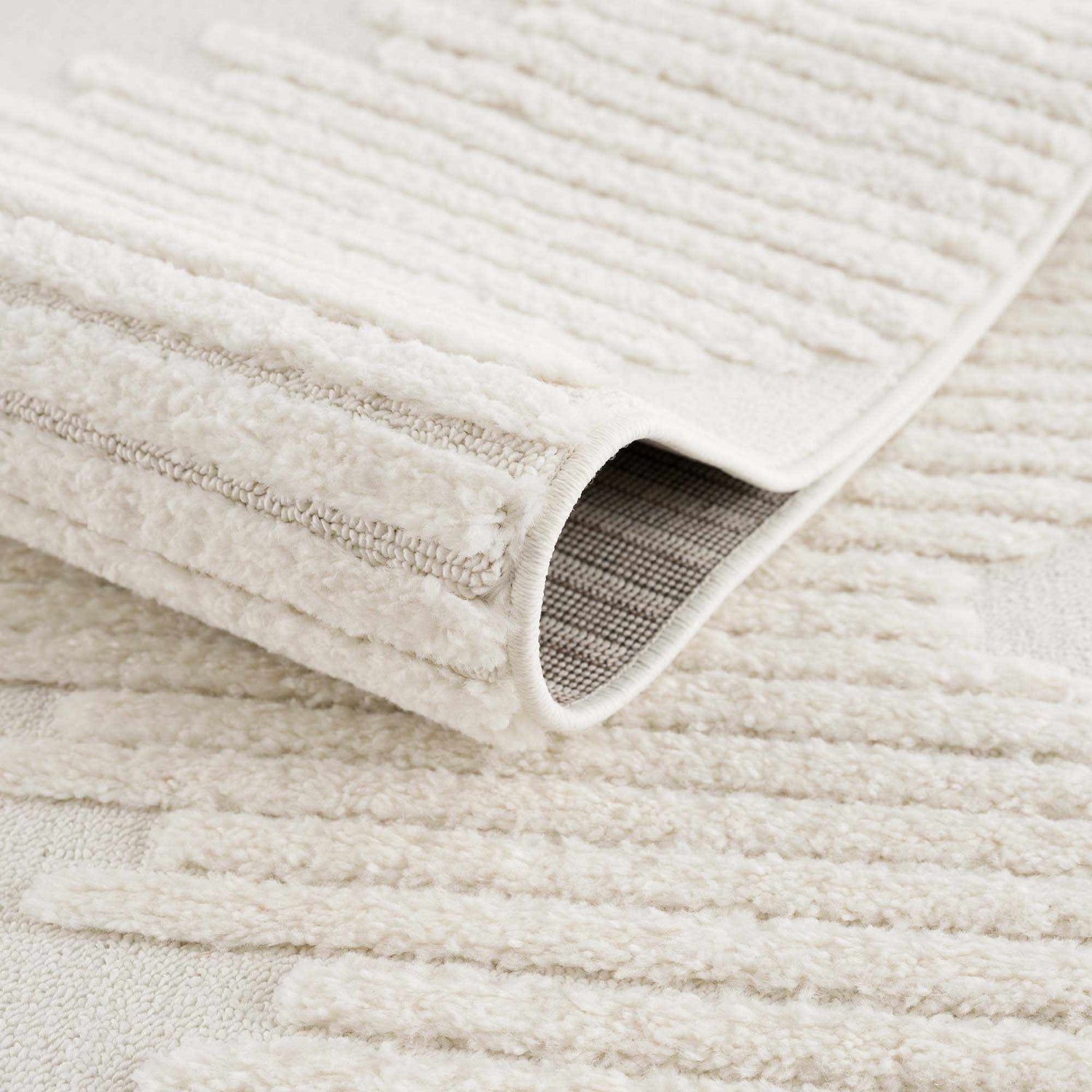 Close-up of the Palimbang Cream 3D Rug showing its geometric pattern, plush texture, and durable machine-woven construction. Fold