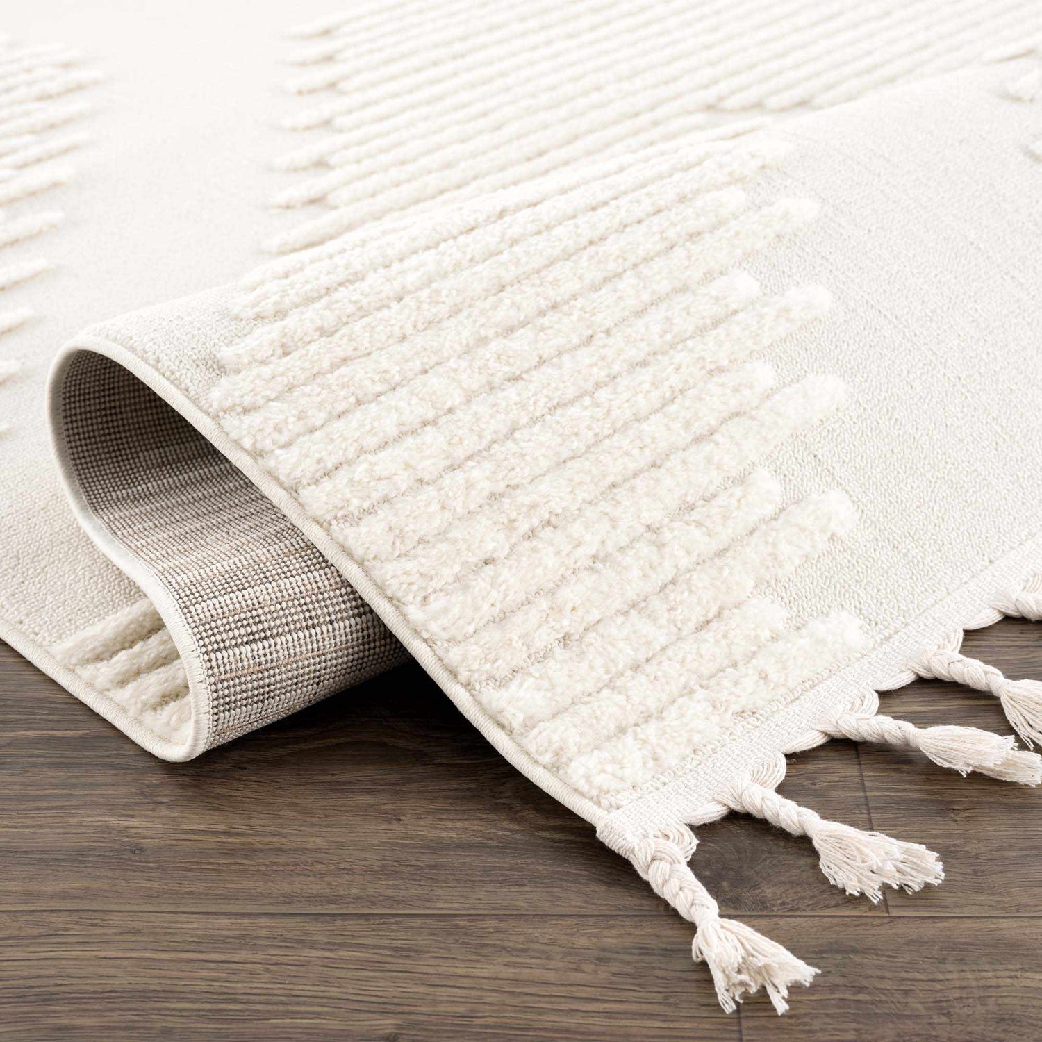 Close-up of the Palimbang Cream 3D Rug showing its geometric pattern, tassels, and textured, machine-woven construction. Fold