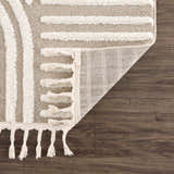 Close-up of the Moise Area Rug showing beige and cream stripes, tassels, and the rug's backing. Fold