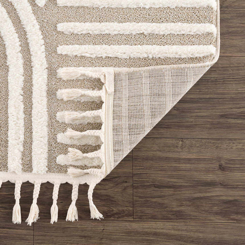 Close-up of the Moise Area Rug showing beige and cream stripes, tassels, and the rug's backing. Fold