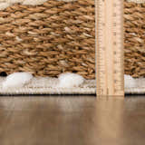 Close-up of the Moise Area Rug showing cream pom-pom details, beige woven texture, and ruler for scale. Pile