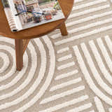 Close-up of the Moise Area Rug, a beige and cream rug with a contemporary geometric pattern and textured, machine-woven construction. Styleshot
