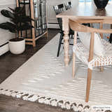Dining room scene with a light wood table and the Palimbang Cream 3D Rug, showcasing its textured geometric design and tassel fringe. Roomscene-Rectangle