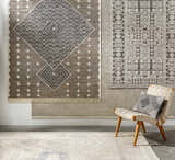 Room scene with charcoal and cream Lodwar Area Rugs on the wall and floor, styled with a woven chair. Styleshot