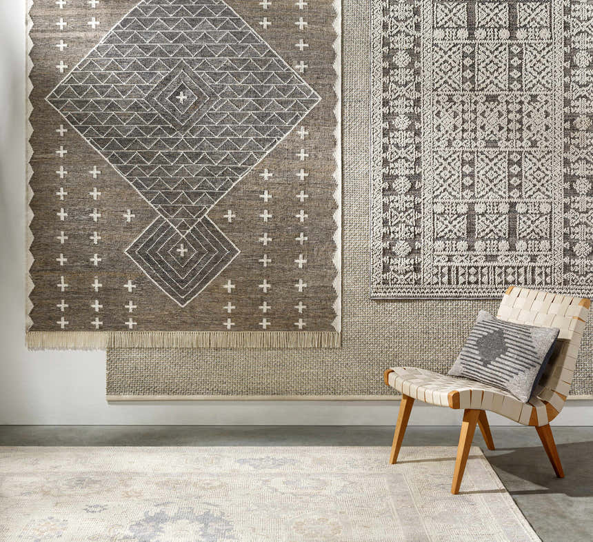 Room scene with charcoal and cream Lodwar Area Rugs on the wall and floor, styled with a woven chair. Styleshot