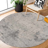 Living room scene with a round Tigrima Ivory 2319 Area Rug, wood floors, chair, and plant creating a cozy, contemporary vibe. Roomscene-Round