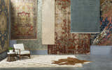Rug showroom featuring a beige Maytown Area Rug with a modern chair and a cowhide rug. Styleshot