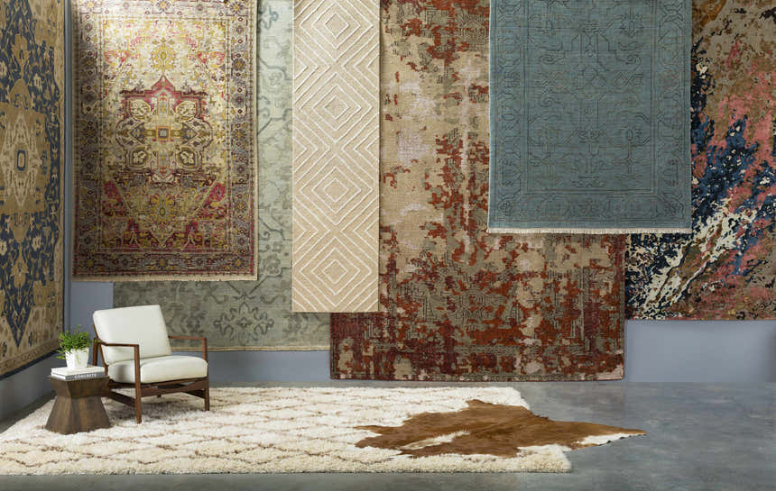 Rug showroom featuring a beige Maytown Area Rug with a modern chair and a cowhide rug. Styleshot