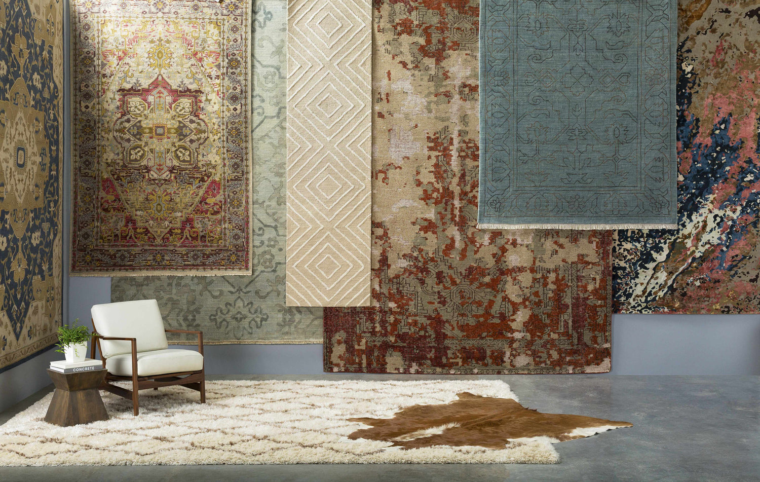 Rug showroom featuring a beige Maytown Area Rug with a modern chair and a cowhide rug. Styleshot