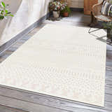 Patio scene with a cream Southwestern style Jove Cream Outdoor Rug, wicker chair, plants, and wood floor. Roomscene-Rectangle