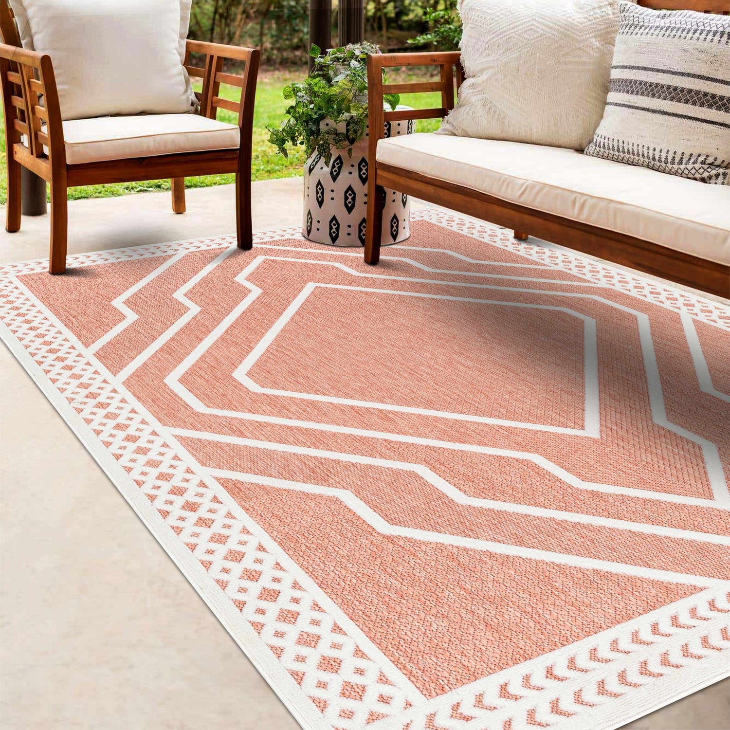 Outdoor patio scene with wood furniture and Anja Orange Outdoor Rug, a clay-colored rug with a geometric white pattern. Roomscene-Rectangle