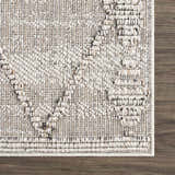 Close-up of Nyla Bone rug showing textured weave, geometric pattern, and bone color on dark wood floor. Contemporary style. Swatch