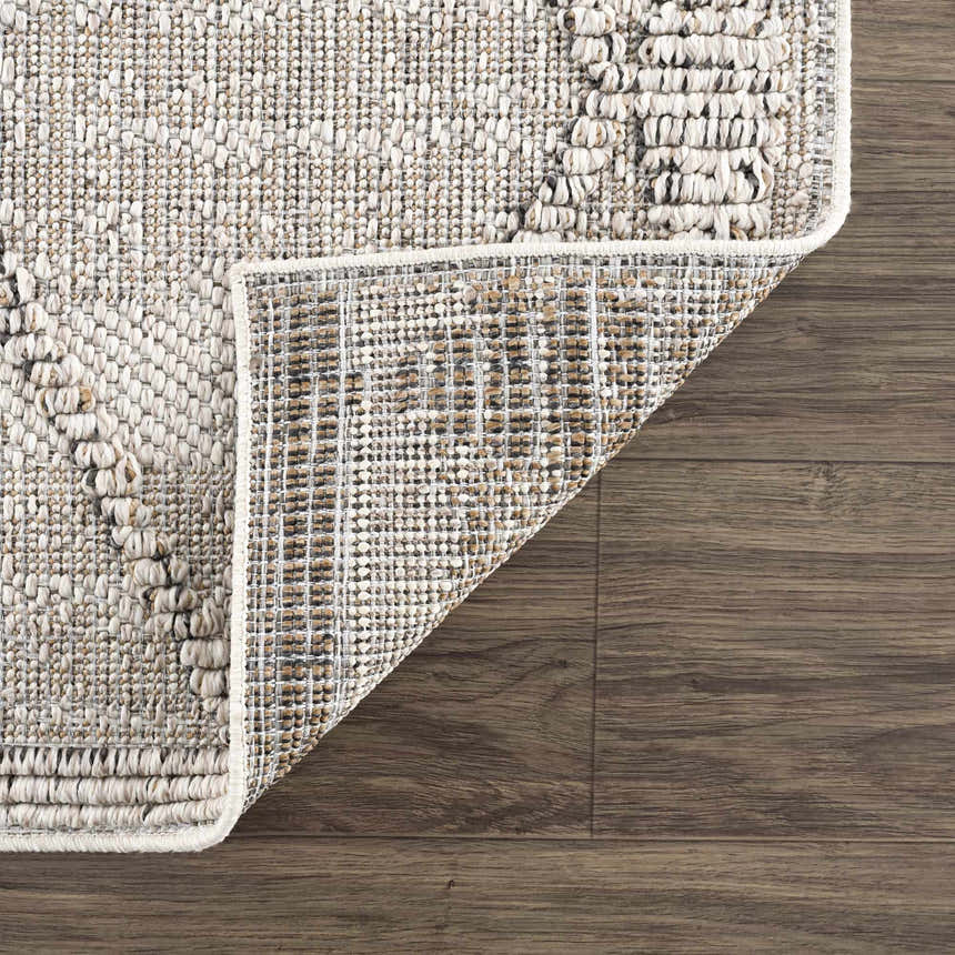 Close-up of the Nyla Bone Indoor Outdoor Rug showing its woven texture, bone color, and backing on a wood floor. Fold