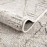 Close-up of the Nyla Bone Indoor Outdoor Rug showing its woven texture and geometric pattern in neutral bone tones. Fold