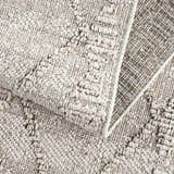 Close-up of the textured Nyla Bone Indoor & Outdoor Rug. Neutral bone color with a woven, raised pattern. Fold
