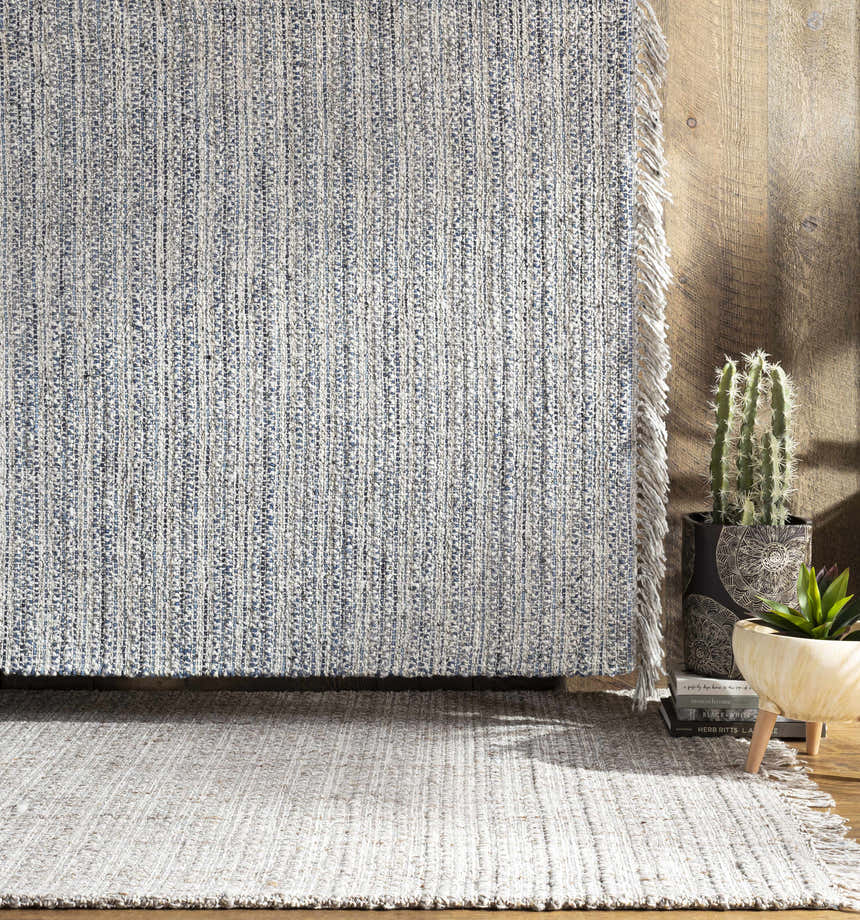 Contemporary living room scene with blue and cream Potterspury Area Rug, wood floor, and potted plants. Styleshot