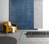 Room scene with a blue Kendall Carpet, gray rugs, and a yellow chair against a white wall. Styleshot