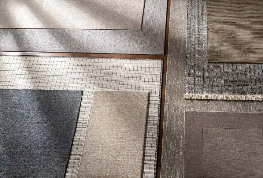 Close-up of various Angie Area Rugs in charcoal, beige, and gray, showing striped, solid, and grid patterns. Styleshot