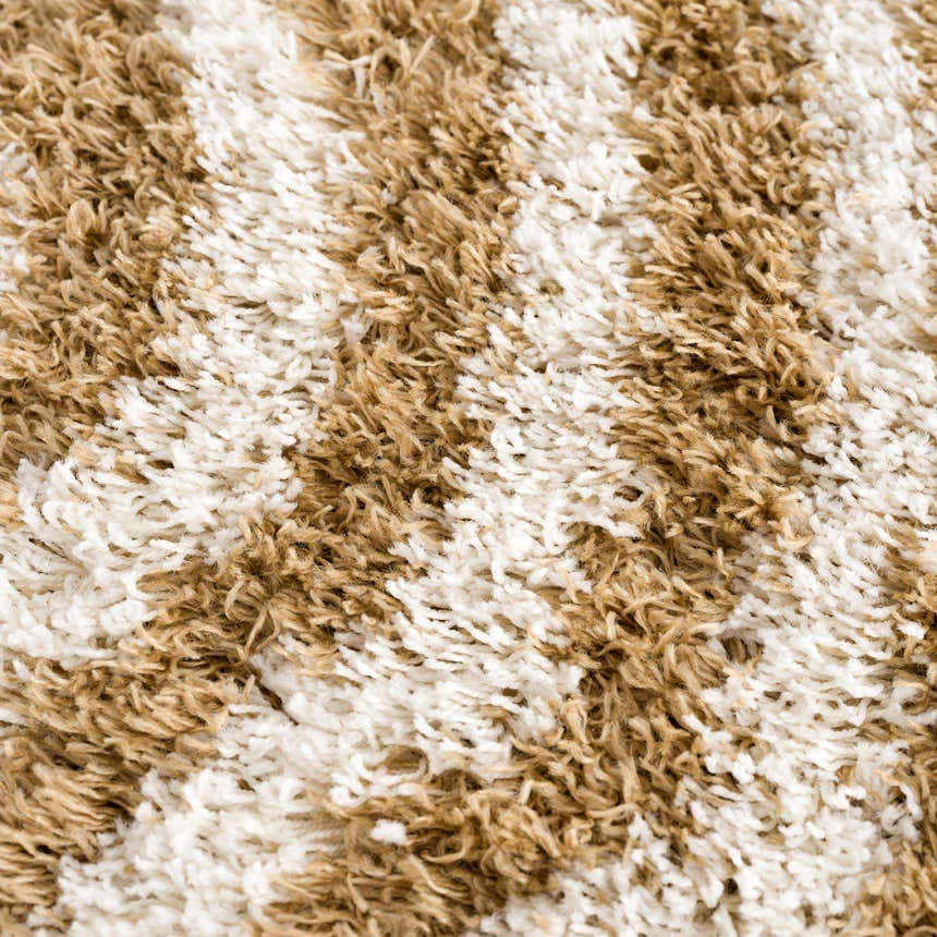 Close-up of the Calup Shag Area Rug showing its bone and dark brown geometric pattern and plush, shaggy texture. Texture
