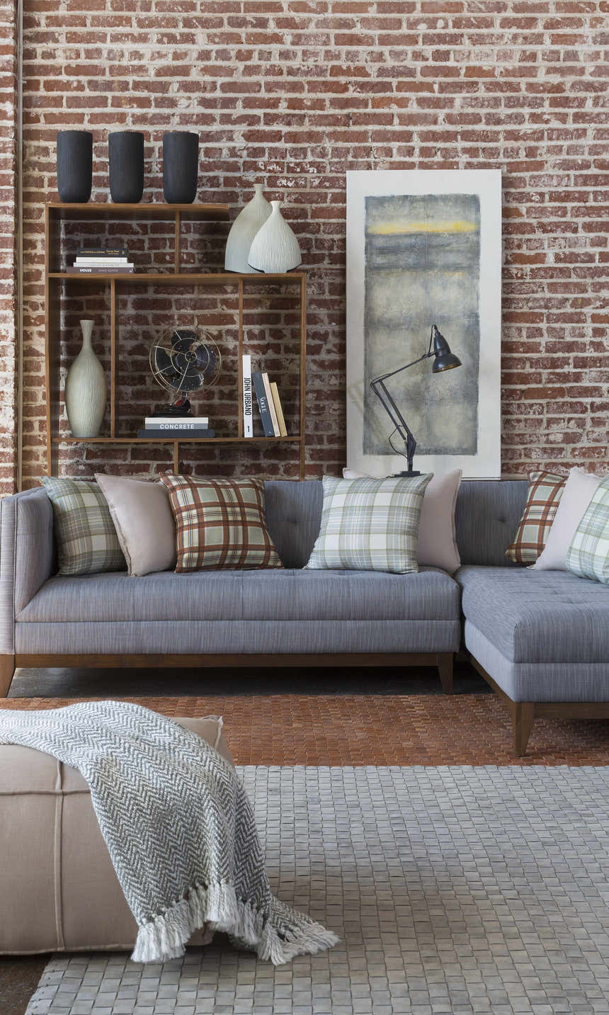 Living room scene with gray Sunburst Area Rug, gray sofa, brick wall, and decorative shelving. Styleshot