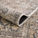 Close-up of the Orsin Washable Area Rug showing its traditional pattern, brown, gray, and white colors, and soft, textured weave. Fold