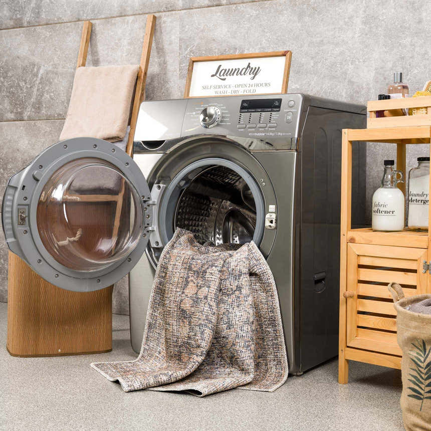 Farmhouse laundry room with gray washer and Orsin Washable Area Rug partially inside. Natural wood accents. Washing-Machine