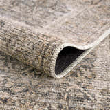 Close-up of the Ohoud Washable Area Rug, showcasing its neutral beige and gray tones, soft texture, and durable machine-woven construction. Fold